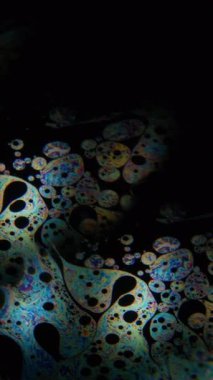 Dikey video. Benzin yağı. Kaleydoskop merceği. Yağ neon mürekkebi üzerindeki renkli, çift taraflı ışık lekesi soyut sıvı arka plan bulanık benzin damlası.