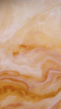 Dikey video. Akrilik karışımı. Boya damlası. Odaklanmamış sarı altın sarısı beyaz renk ışıltılı ıslak doku emülsiyon dalgası soyut arkaplan üzerine dökülüyor.