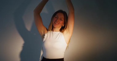 Pozitif yaşam tarzı. Kadın zarafeti. Huzurlu, huzurlu bir kadın hipnotik el hareketlerinden hoşlanıyor. Gölge ışığı arka planındaki saçlara dokunuyor..