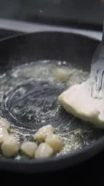 Dikey video. İstiridye hazırlıyorum. Deniz tarağı pişiriyorum. Siyah sıcak tavada kızaran soyulmuş protein bileşenleri. Şef lezzetli soslar için tereyağı ekliyor..