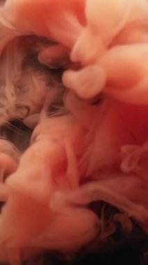 Dikey video. Bulut karışımı. Boya patlamış. Siyah arka plana yayılmış portakallı puf spreyi. Soyut su rengi lekesi patlaması bulanık fantezi sisi.