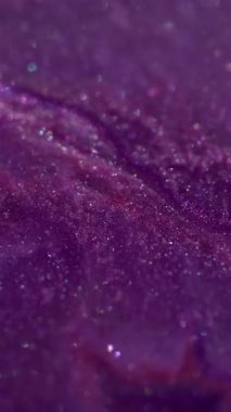 Dikey video. Parıltı karışımı. Mürekkep arkaplanı. Suyun kimyasal yapısında çözünmüş mor renkli lekeler soyut bokeh sanatına yayılıyor..