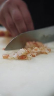 Dikey video. Karides hazırlanıyor. Deniz ürünleri doğramak. Şefin elleri gurme yemeği için karides eti pişiriyor. Beyaz fotokopi alanında sağlıklı yemek için suşi malzemeleri.