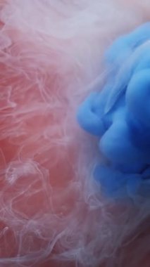 Dikey video. Bulut karışımı. Boya patlamış. Kahverengi beyaz sıvıya yayılmış mavi puf spreyi. Soyut su rengi patlaması fantezi arka planını bulanıklaştırır.