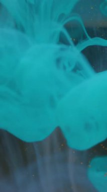 Dikey video. Duman parçacıkları sıçrat. Su bulutu küresi. Odaklanmamış mavi altın rengi sıvı doku soyut arkaplana yayılan toz boyası.