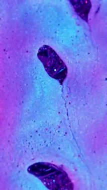 Dikey video. Mürekkep akışı. Boya akışı. Odaklanmamış mor neon renkli su kimyasal diş minesi akrilik kabarcıklar soyut desenli arka plana damlıyor..