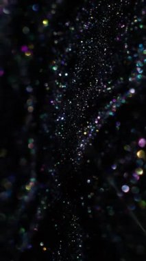 Dikey video. Bokeh soyutlaması. Parlak işaret fişeği. Odaklanmamış altın mavisi mor renk koyu siyah festival sanat arka planında parıltılı efekt.