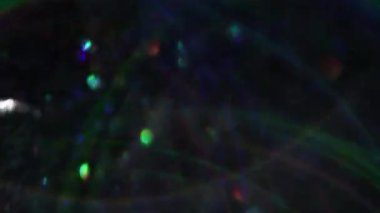 Bokeh ışığı. Odaklanmamış çelenk. Lens parlamaları ışık parçalarını kıvılcımlar. Bulanık siyah soyut arka planda yüzen çok renkli gölgeler..