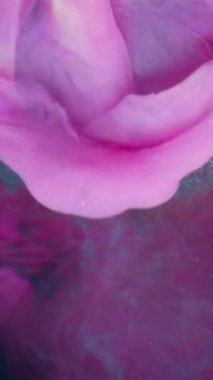 Dikey video. Işıldayan sıvı. Parlak dalga. Pembe boya damlaları düşen cam tırtıklı küre. Yüzen lüks mavi boya soyut su bulanıklığı koyu arkaplan.