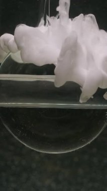 Dikey video. Küre boyası. Sıçrama akışı. Odaklanmamış beyaz renk bulut dokusu şeffaf yuvarlak baloncuk soyut sanat koyu siyah arkaplan üzerinde yüzüyor.