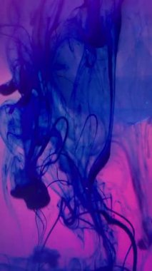 Dikey video. Neon mürekkebi. Cam kristal. Floresan mavi duman pigmenti elması döküyor. Pembe parlak sanat eseri arka planda renk değiştiren su lensi.