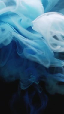 Dikey video. Sis sıvısı. Haze boyası. Mavi gri duman hipnotik kıvrım fırtınası sıvıda akıyor. Boyalı su pigmenti soyut siyah arkaplan.