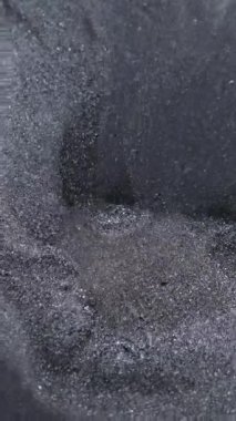Dikey video. Parlak akış. Mürekkep arkaplanı. Odaklanmamış gümüş rengi kimyasal sıvı karışım su dokusu sıçrama damlası soyut siyah sanata dökülüyor.