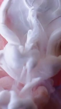 Dikey video. Puf boyası. Duman dalgası. Beyaz sprey mat sıvı boya turuncu soyut çözünmüş sisli su yüzeyi arkaplanını yayıyor.