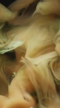 Dikey video. Duman sıvısı. Mürekkep sisi. Sarı yeşil renk akışı fantezi pigmenti çözünmüş su siyah sanat soyut mistik arka plana düşer.