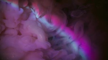 Mürekkep akışı. Renkli su. Odaklanmamış mor mavi parlak parlak neon gökkuşağı sıvısı soyut koyu siyah ışık sanat arka planında yüzüyor..