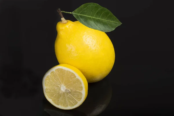 lemon on black background with green leaves