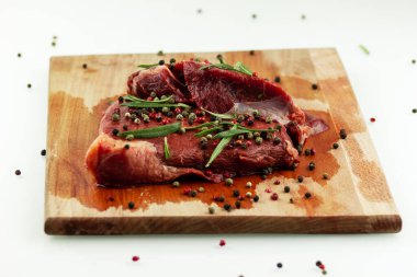  Biber ve biberiyeyle tatlandırılmış ahşap bir tahtada biftek.