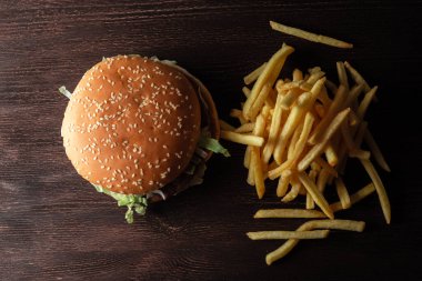 Bir hamburger ve ahşap bir arka planda bir yığın patates kızartması.