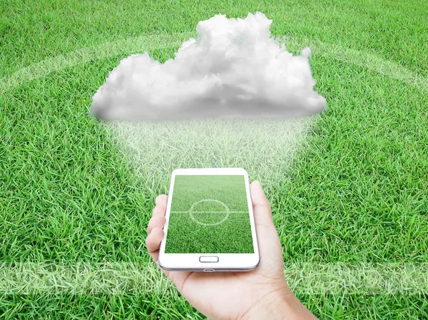Bulut ve futbol konsepti, arka planda futbol sahası olan cep telefonu..