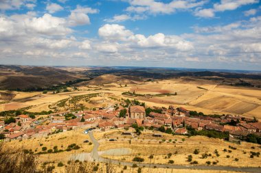 İspanya, Atienza, Guadalajara 'yı çevreleyen kayan tepelerin manzarası, açık hava keşfi ve fotoğrafçılık için mükemmel, parlak bir gökyüzü altında antik kalıntıları ve çimenli araziyi gösteriyor..