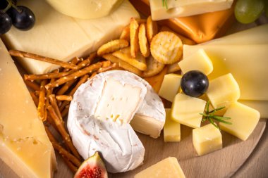 Çeşitli peynirler yuvarlak ahşap tahta plaka Camembert peyniri peyniri meşe, sert peynir dilimleri, ceviz, üzüm, kraker, ekmek, kekik, ahşap arka plan kabuğu rendesi. Üstten görünüm