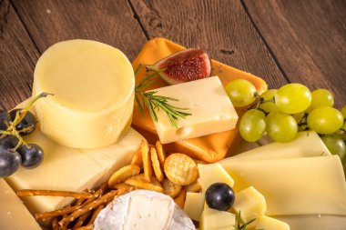 Çeşitli peynirler yuvarlak ahşap tahta plaka Camembert peyniri peyniri meşe, sert peynir dilimleri, ceviz, üzüm, kraker, ekmek, kekik, ahşap arka plan kabuğu rendesi. Üstten görünüm