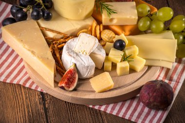 Çeşitli peynirler yuvarlak ahşap tahta plaka Camembert peyniri peyniri meşe, sert peynir dilimleri, ceviz, üzüm, kraker, ekmek, kekik, ahşap arka plan kabuğu rendesi. Üstten görünüm