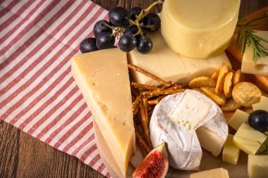 Çeşitli peynirler yuvarlak ahşap tahta plaka Camembert peyniri peyniri meşe, sert peynir dilimleri, ceviz, üzüm, kraker, ekmek, kekik, ahşap arka plan kabuğu rendesi. Üstten görünüm