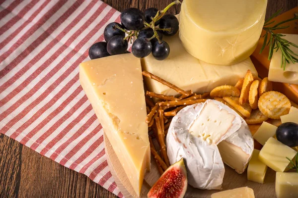 Çeşitli peynirler yuvarlak ahşap tahta plaka Camembert peyniri peyniri meşe, sert peynir dilimleri, ceviz, üzüm, kraker, ekmek, kekik, ahşap arka plan kabuğu rendesi. Üstten görünüm