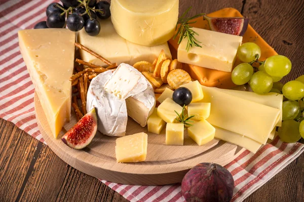 Çeşitli peynirler yuvarlak ahşap tahta plaka Camembert peyniri peyniri meşe, sert peynir dilimleri, ceviz, üzüm, kraker, ekmek, kekik, ahşap arka plan kabuğu rendesi. Üstten görünüm