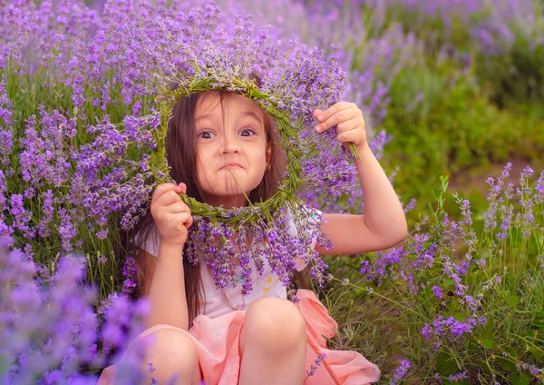 Ein schönes kleines Mädchen macht eine Lavendelkrone — Stockfoto