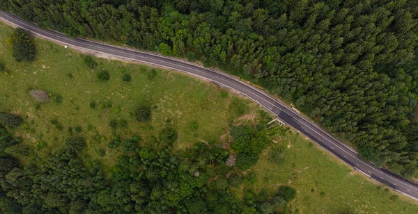 Vista aérea sobre a estrada da montanha que atravessa a paisagem florestal. T — Fotografia de Stock