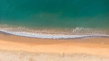 Kumlu plajda hava manzarası. Şemsiyeler, kum, köprü ve 