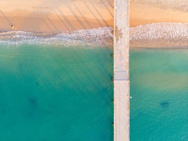 Kumlu plajda hava manzarası. Şemsiyeler, kum, köprü ve 