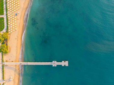 Kumlu plajda hava manzarası. Şemsiyeler, kum, köprü ve 