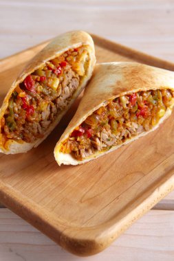 Burrito sarar et, fasulye ve ahşap tahta üzerinde sebze ile