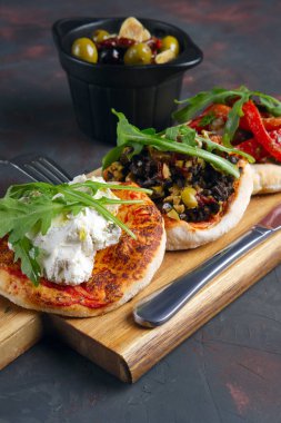 Lezzetli tapas ayarlayın. Keçi peyniri, doğranmış zeytin ve fındık, kurutulmuş domates ve kavrulmuş dolmalık biber ile küçük sandviçler.