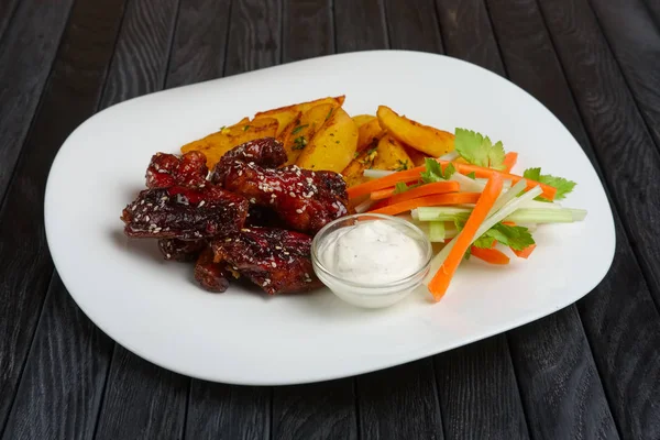 Buffalo chicken wings with fried potato and carrot and celery sticks