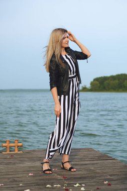 Rüzgarlı havalarda iskelede duran gülümseyen güzel genç kadın 