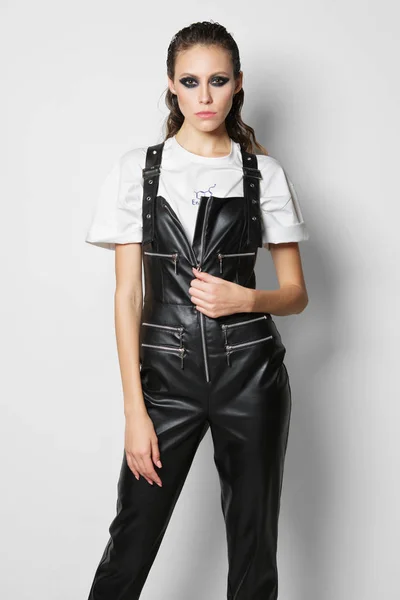 Flicka Faux Läder Overall Och Shirt Posing Nära Vit Vägg — Stockfoto