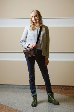 Sevimli öğrenci kız ceket, kot pantolon ve bot ile omuz çantası ondoors