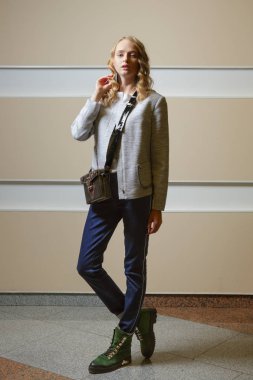 Sevimli öğrenci kız ceket, kot pantolon ve bot ile omuz çantası ondoors