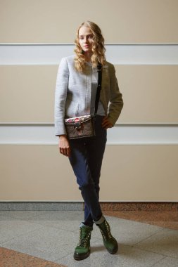 Sevimli öğrenci kız ceket, kot pantolon ve bot ile omuz çantası ondoors