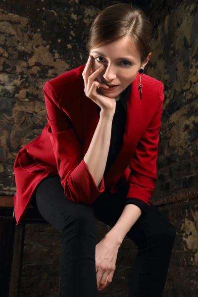 Pretty girl propping chin sitting on chair in the room with grunge brick walls