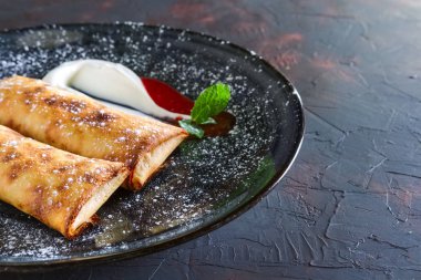 Tatlı krep ile lor dolması ve ekşi krema ve çilek reçeli ile dekore edilmiş