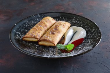 Tatlı krep ile lor dolması ve ekşi krema ve çilek reçeli ile dekore edilmiş