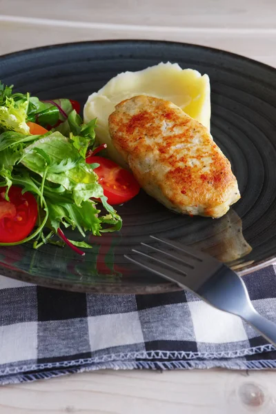 Fried chicken patty with mashed potato and fresh arugula, tomato and spinach