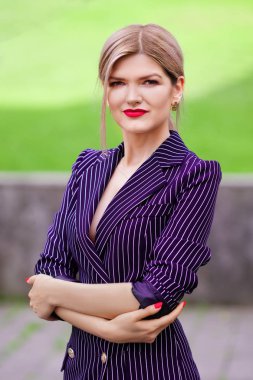 Açık şerit ceketli kendine güvenen Bayan portresi. Çapraz elle bir sokakta duran güzel kadın.