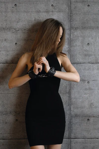 Портрет красивой девушки в черном платье и кожаных наручниках — стоковое фото